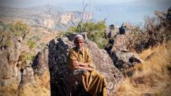 Hassan Bah avec en arrière plan la falaise de Douki fait partie de ces pionniers du tourisme de Guinée. Dans son village de Fouta-Djalon, à 50 kilomètres de Pita, il accueille les touristes depuis 20 ans.