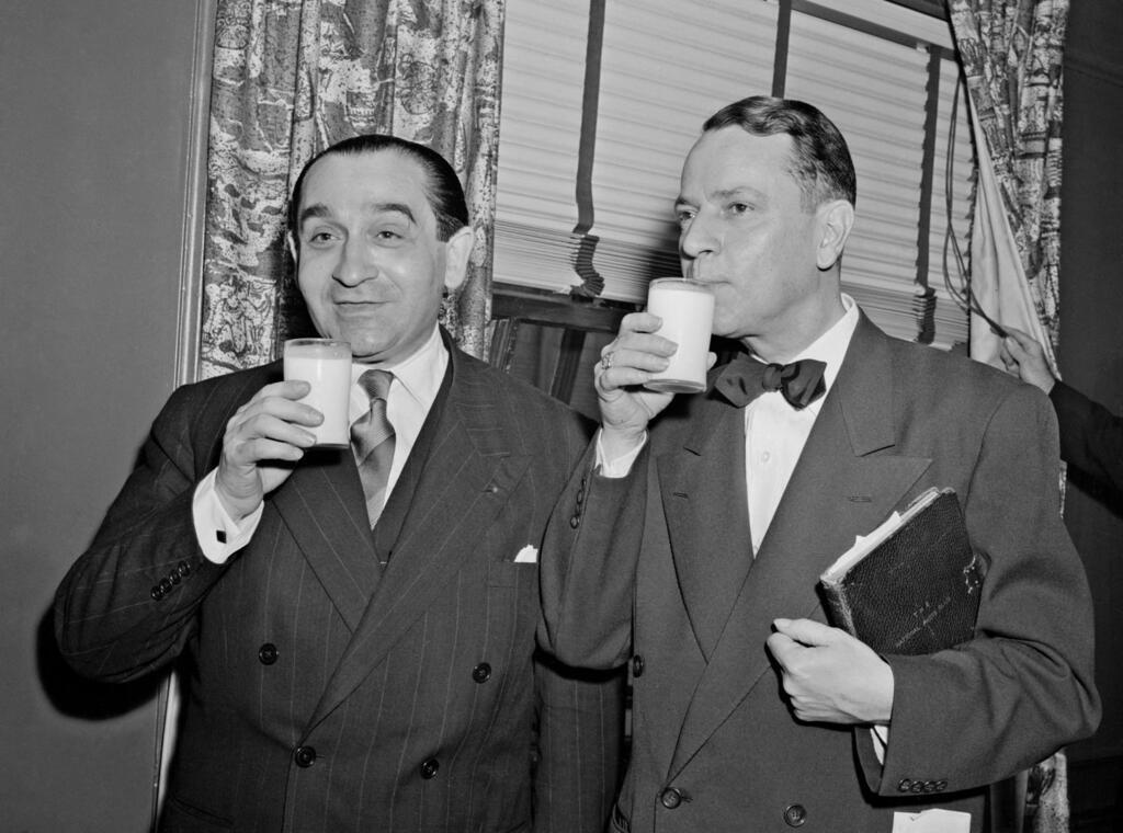 O presidente do Conselho de Ministros (antigo nome dado ao cargo de primeiro-ministro na França) Pierre Mendès France (à esquerda) bebe leite com Tony Vacaro, presidente do Clube Nacional de Imprensa, em 22 de novembro de 1954, durante uma viagem oficial aos Estados Unidos.