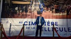 Le réalisateur guinéen Thierno Souleymane pose pieds nus devant l'affiche de son film «Au cimetière des pellicules».