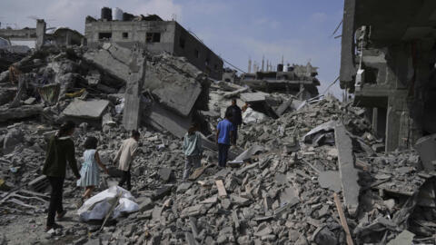 تصویری از چند فلسطینی بر ویرانه‌های ناشی از حملات اسرائیل در شمال نوار غزه