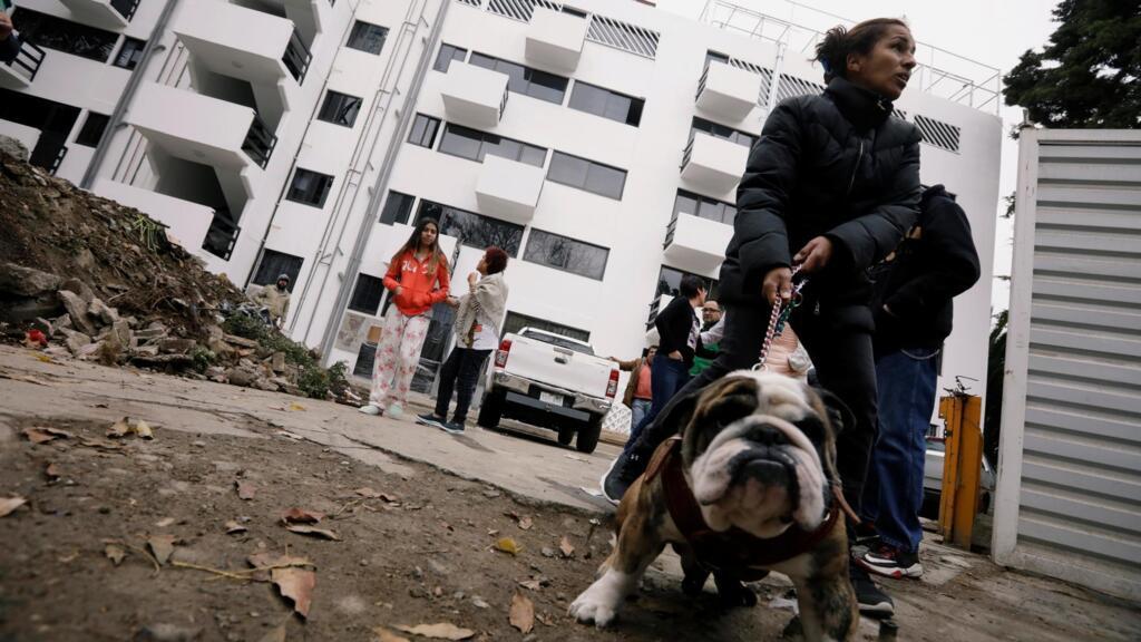 Une femme promène son chien près de son logement temporaire, dans qu'un quartier de Mexico, qu'elle habite depuis le tremblement de terre de 2017, en attente d'être relogée.