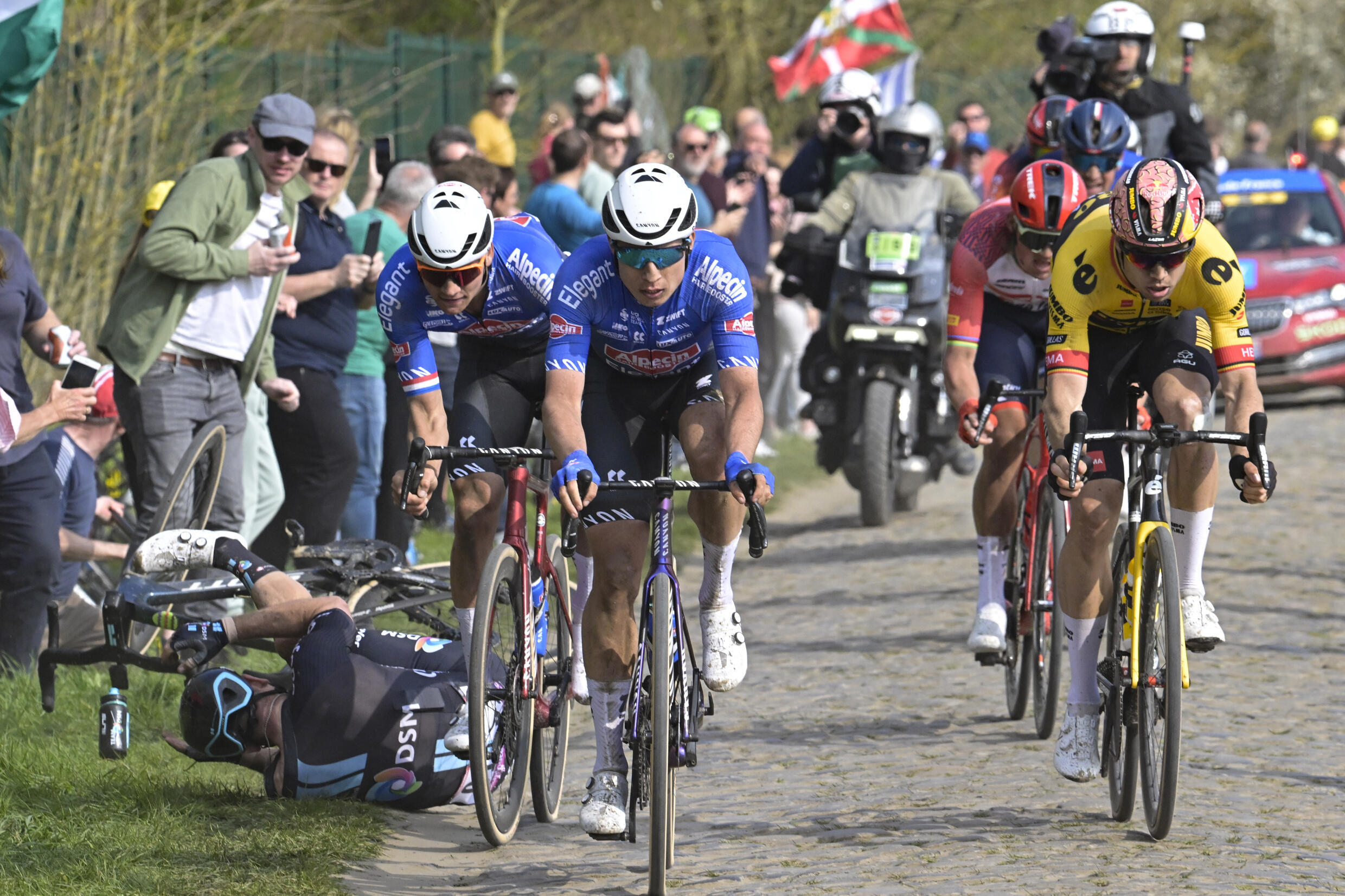 Los ciclistas Jasper Philipsen, Mathieu Van Der Poel y Wout Van Aert ruedan mientras John Degenkolb sufre una caída en la clásica París-Roubaix, en Francia, el 9 de abril de 2023