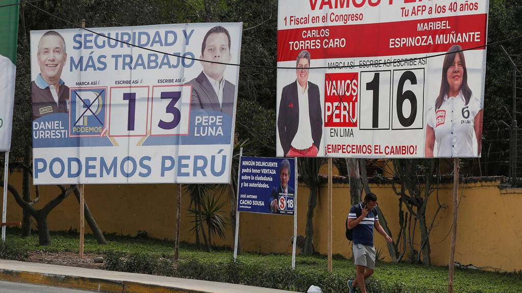 Un homme passe devant les affiches de la campagne politique alors que les Péruviens se rendent aux urnes dimanche pour choisir un nouveau Congrès, à Lima au Pérou, le 25 Janvier 2020.