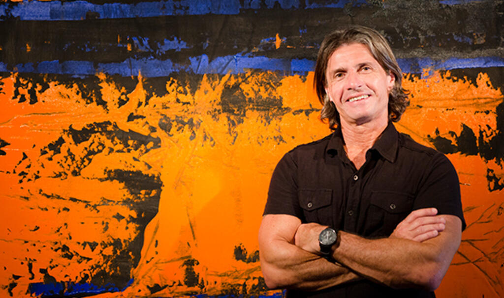O artista plástico gaúcho Norberto Noschang diante de sua obra de cores fortes.