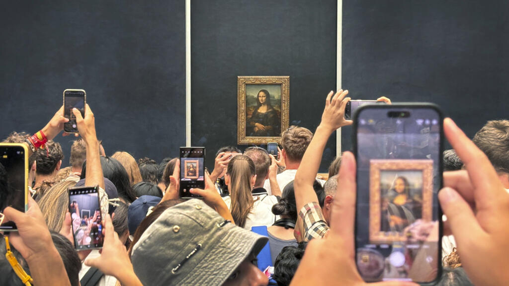 Turistas se aglomeram para fotografar "Mona Lisa", obra de Leonardo da Vinci, exposta no Museu do Louvre, em Paris. Imagem de 8 de agosto de 2024.