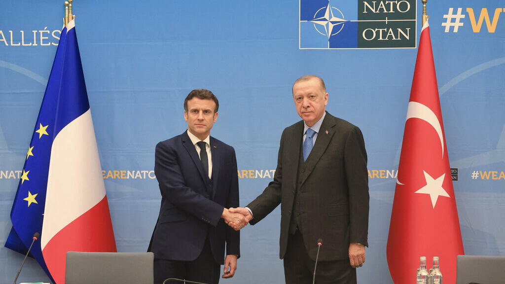 French President Emmanuel Macron and Turkish President Tayyip Erdogan shake hands as they attend a bilateral meeting ahead of a NATO summit to discuss Russia's invasion of Ukraine.