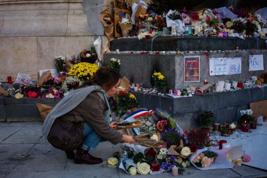 Une femme dépose des fleurs devant un mémorial improvisé en hommage aux victimes des attentats du 13-novembre, place de la République, à Paris, le 11 novembre 2025.