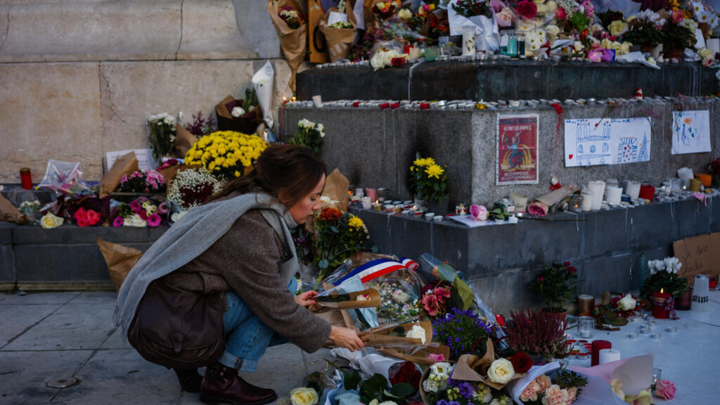 Une femme dépose des fleurs devant un mémorial improvisé en hommage aux victimes des attentats du 13-novembre, place de la République, à Paris, le 11 novembre 2025.