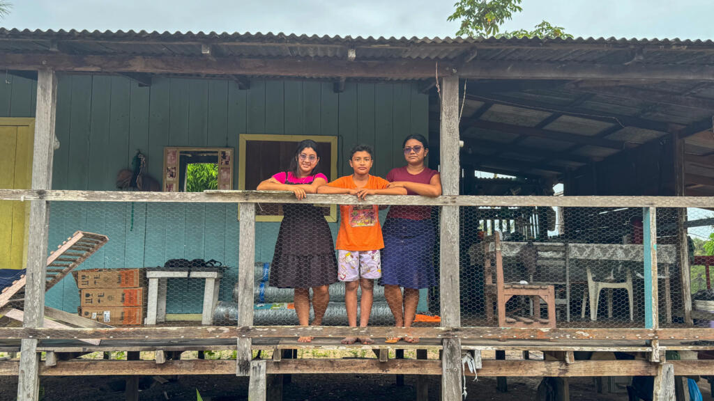 Taila Pinheiro, agente de saúde em Paraíso, posa com os filhos em frente à casa da família, sobre palafitas.