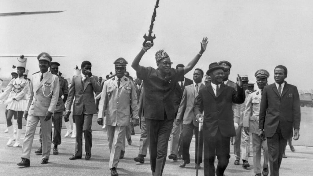 Joseph Desire Mobutu (plus tard Mobutu Sese Seko-C), président du Congo-Kinshasa (Zaïre, aujourd'hui République démocratique du Congo), salue la foule alors qu'il est accueilli par le président de la République centrafricaine Jean-Bedel Bokassa (2e à droite), à son arrivée à l'aéroport de Bangui en janvier 1971.