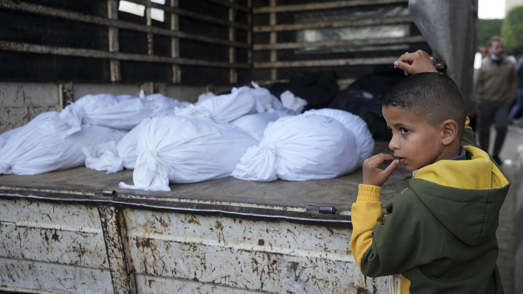 Um menino palestino ao lado dos corpos de parentes mortos nos bombardeios israelenses na Faixa de Gaza, em frente ao necrotério do Hospital Al Aqsa, em Deir al Balah, no sábado, 24 de fevereiro de 2024.