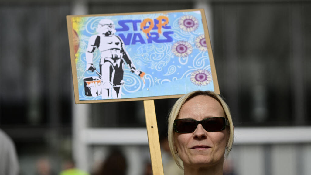 Mulher exibe cartaz com mensagem "Parem as guerras" durante manifestação em Berlim em 30 de março de 2024.