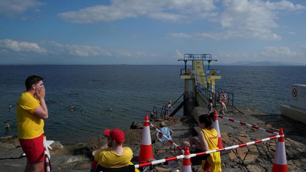 Des sauveteurs en mer surveillent le plongeoir, inaccessible à cause du Covid-19, sur la plage à Galway en Irlande, le 11 août 2020.