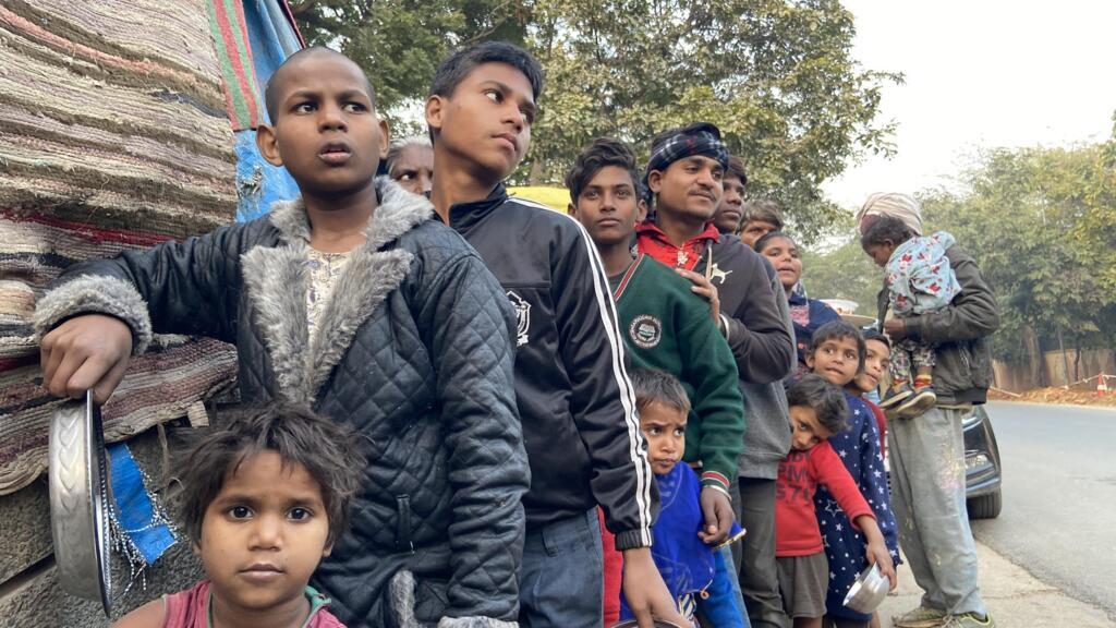 People from a shanty in Delhi queuing up for hot food served by the Robin Hood Army.