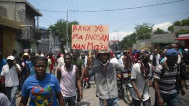 Sur la pancarte, on peut lire en créole : « Les banques ne sont pas innocentes dans notre misère », lors d'une manifestation pour exiger la démission du Premier ministre haïtien Ariel Henry et un appel à une meilleure qualité de vie. Port-au-Prince, Haïti, le mercredi 7 septembre 2022.