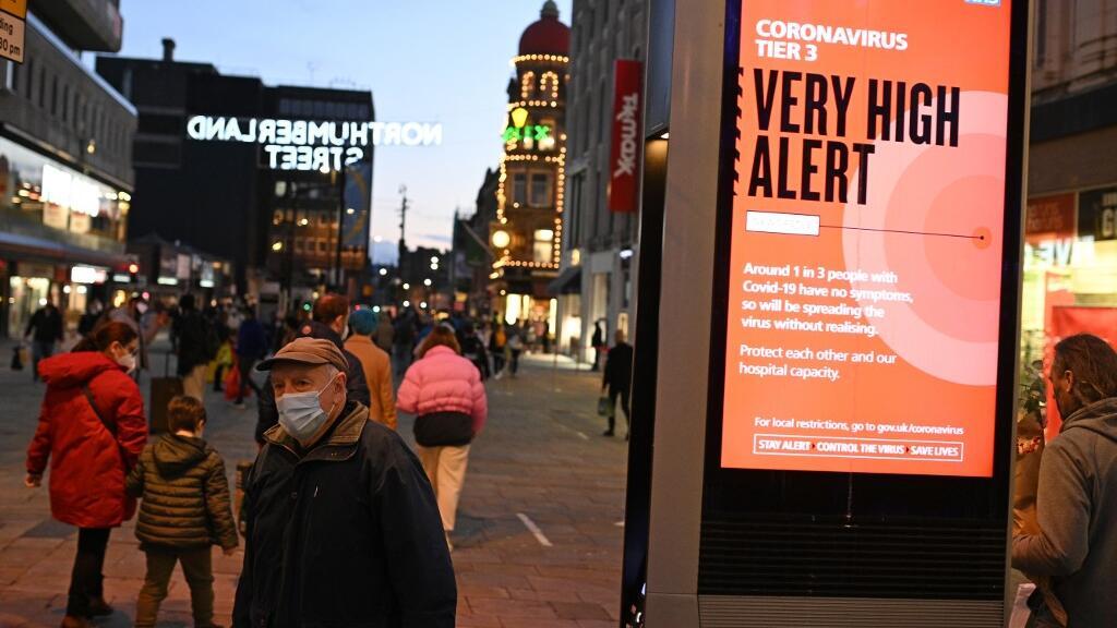 Pedestre passa ao lado de alerta sobre perigo de infecção pelo coronavírus em Newcastle upon Tyne,no noroeste da Inglaterra, em 19 de dezembro de 2020.