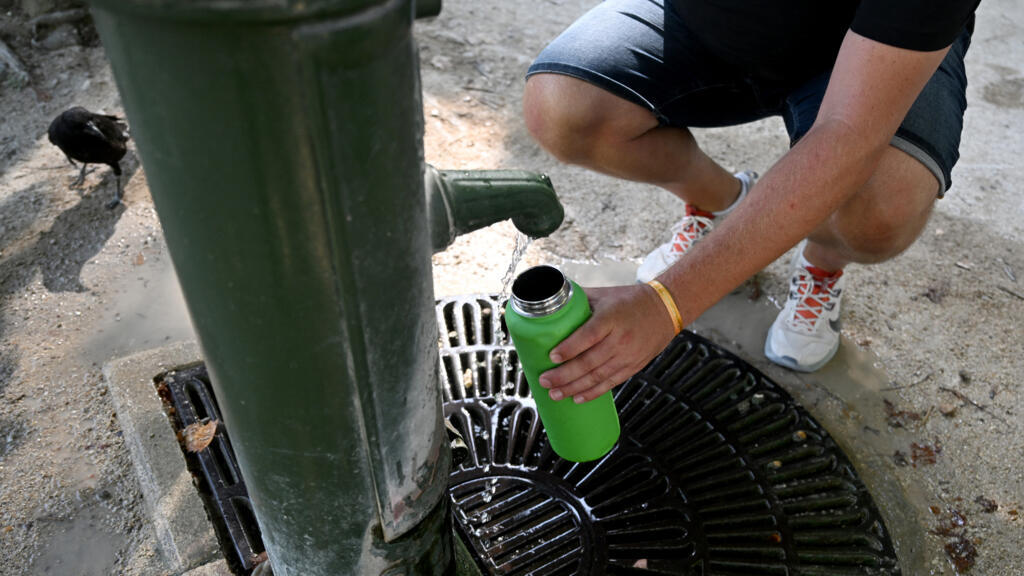 Un piéton remplit sa gourde dans le jardin des Tuileries à Paris, le 11 août 2025, en pleine vague de chaleur en Europe.