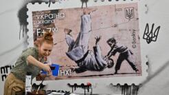 Người dân đến bưu điện thành phố Kiev ngày 24/02/2023, để xem con tem mới, mô tả võ sĩ judo nhỏ quật ngã người đàn ông lực lưỡng (ngụ ý chỉ Putin). Phía dưới tem có dòng chữ lên án Putin. Nền tranh là bức tường nhà ở Borodyanka, biểu tượng tội ác chiến tranh Nga.