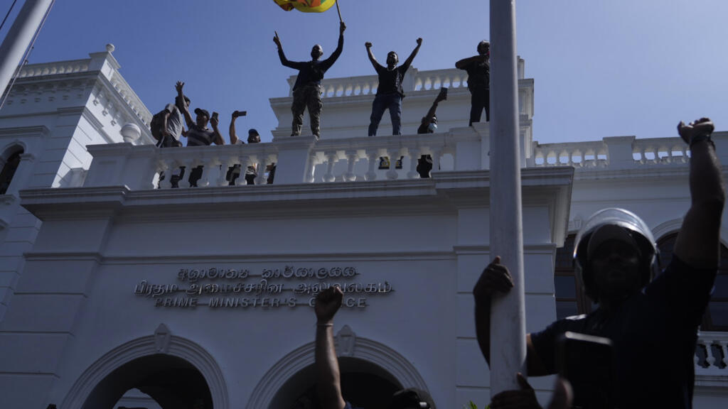 Des manifestants sri-lankais brandissent le drapeau national depuis le toit des bureaux du Premier ministre pour réclamer sa démission, à Colombo, le 13 juillet 2022.