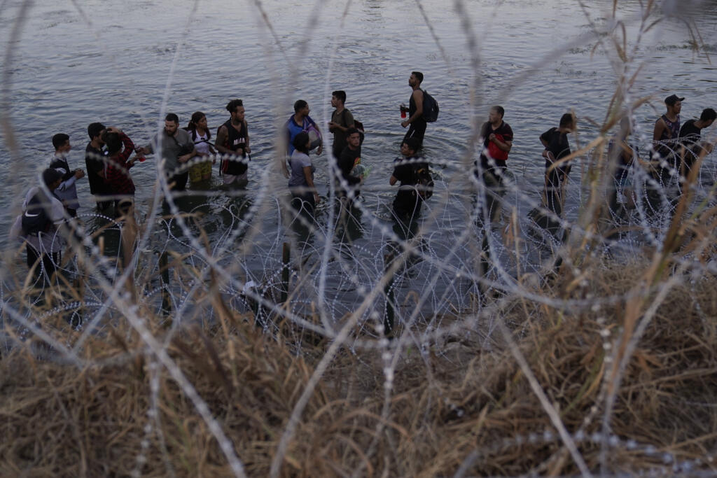 Des migrants en provenance du Mexique, après la traversée du Rio Grande, s'apprêtent à franchir un mur de barbelés, à Eagle Pass (Texas).