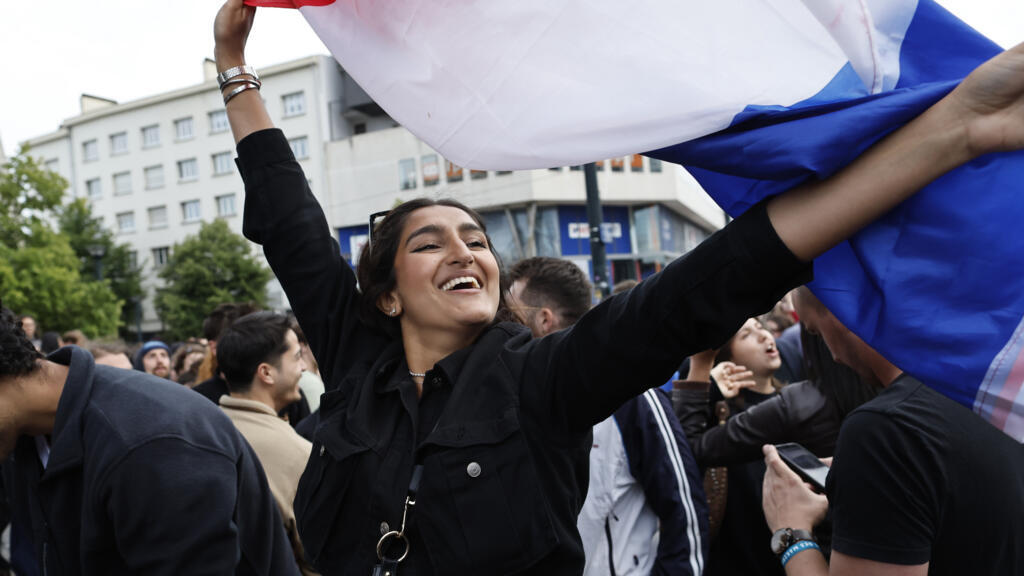 Mulher agita bandeira francesa após resultados do segundo turno das eleiçéoes legislativas na França, com vitória da coligação de esquerda. Paris, 7/7/24.