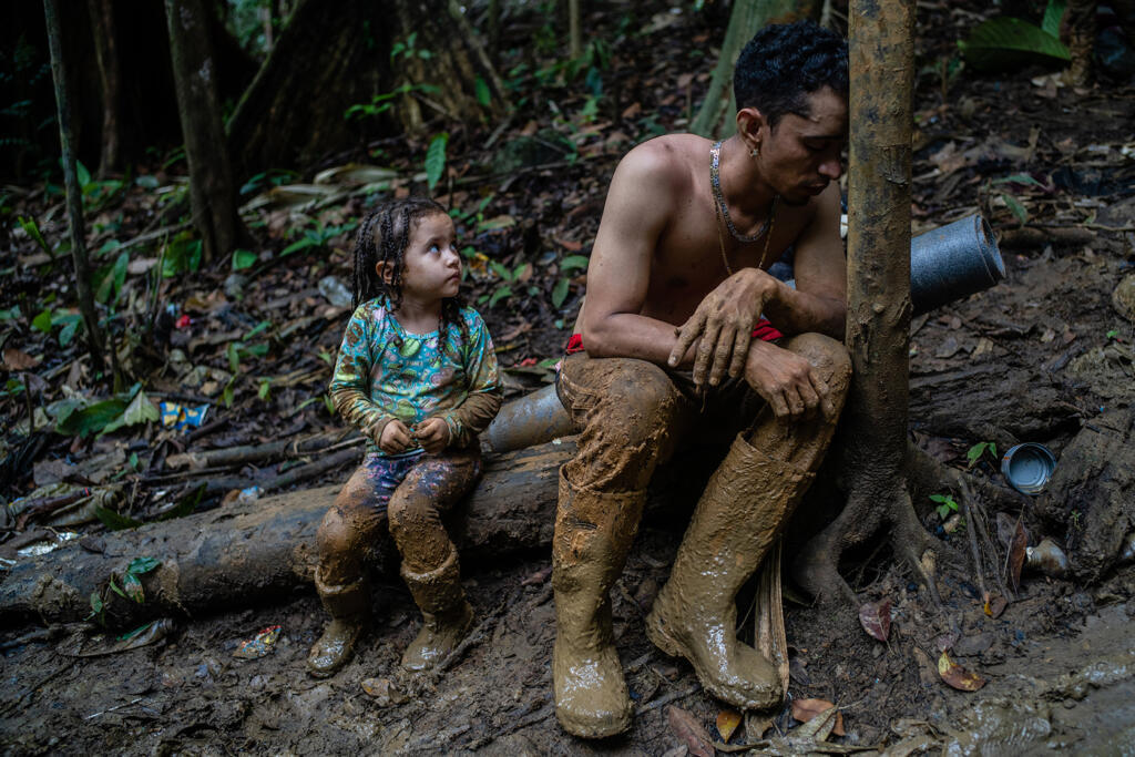 Luis Miguel Arias, 28 anos, e sua filha Melissa, 4 anos, originários da Venezuela, fazem uma pausa enquanto escalam uma colina na região de Darién, entre a Colômbia e o Panamá. O pai estava extenuado de cansaço.