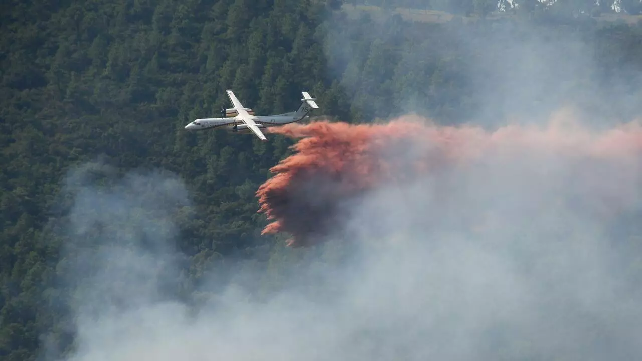 Un avión de Securite Civile Bombardier Dash 8-Q400MR lanza retardante de incendios sobre un incendio forestal humeante en la ladera cerca de Grimaud, en el departamento de Var, sur de Francia, el 18 de agosto de 2021. Cientos de bomberos lucharon por tercer día el 18 de agosto para contener el peor incendio forestal del verano en Francia, cerca de la estación balnearia de la Riviera de Saint-Tropez.