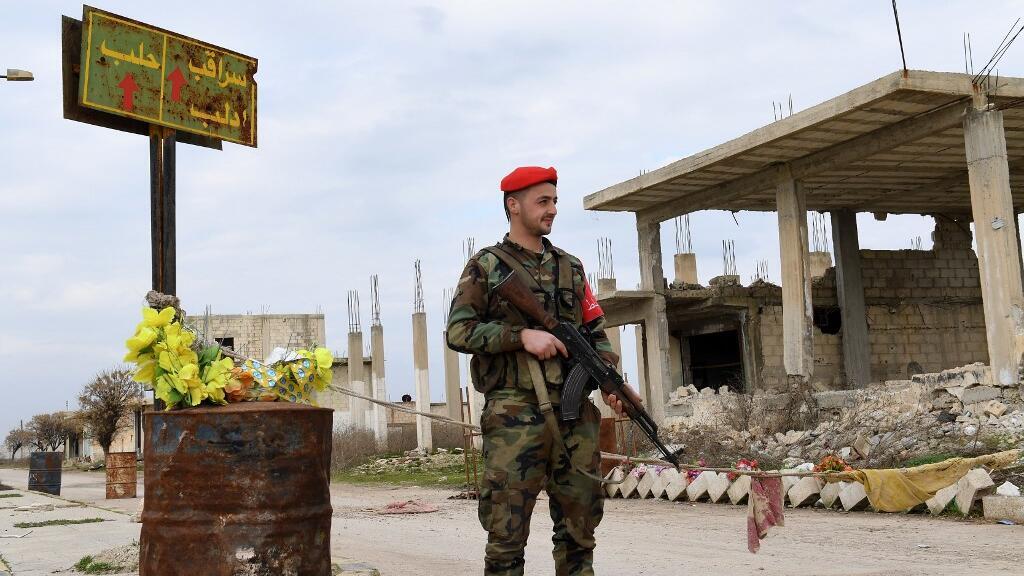 Un soldat de l'armée syrienne monte la garde à côté d'un panneau indiquant "Saraqeb", dans la ville de Tall Sultan, dans la province d'Idleb.