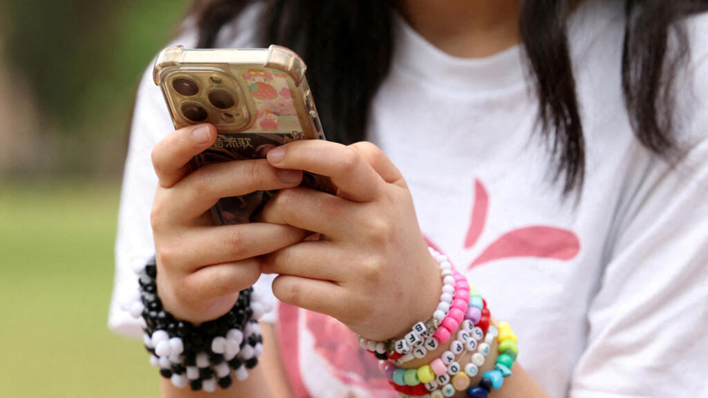 Une jeune australienne pose avec son téléphone après une interview au sujet de l'interdiction des réseaux sociaux pour les utilisateurs de moins de 16 ans en Australie, qui doit entrer en vigueur le 10 décembre, à Sydney, en Australie, ici le 22 novembre 2025.