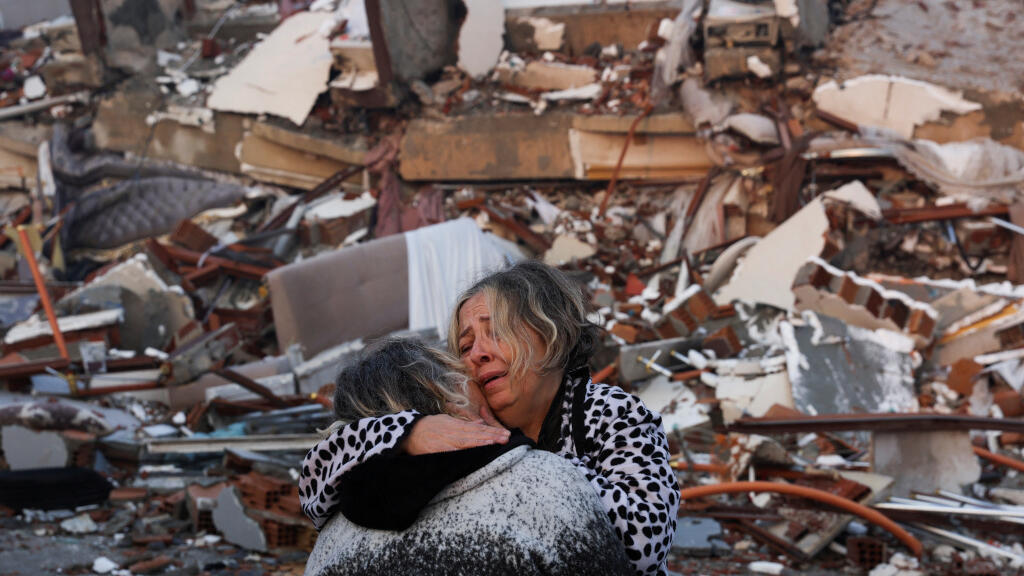 People embrace near rubble in Hatay province, Turkey, on 7 February 2023, after a huge earthquake the day before.