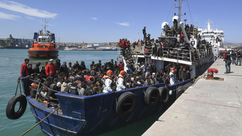 Migrantes esperam para desembarcar de navio no porto siciliano de Catânia, em 12 de abril de 2023