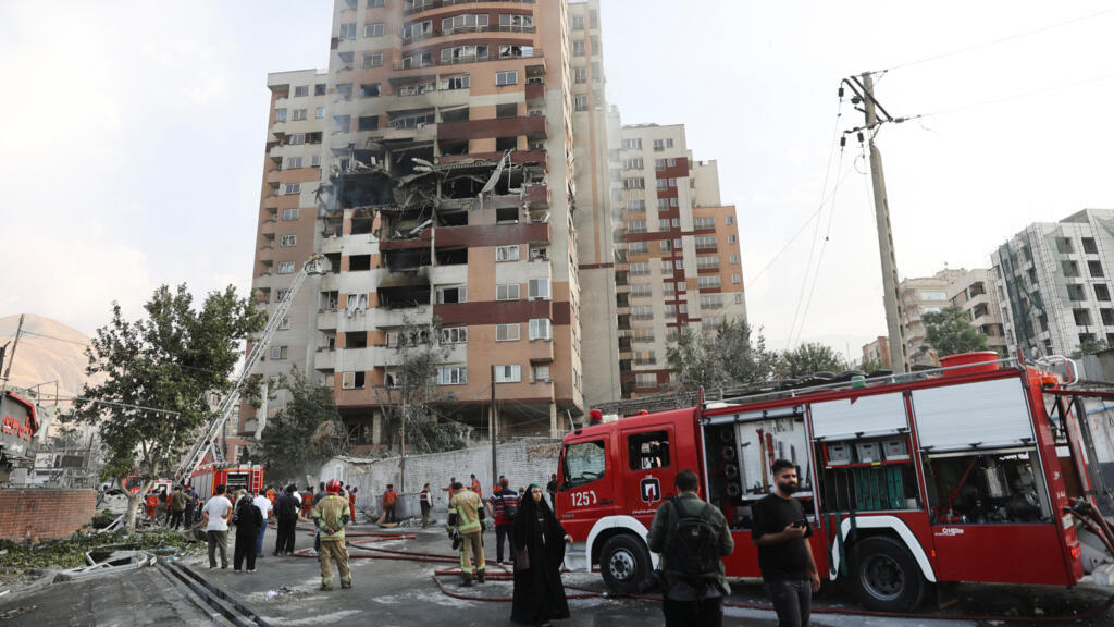 Des pompiers travaillent sur les lieux d'un bâtiment endommagé à la suite de frappes israéliennes, à Téhéran, en Iran, le 13 juin 2025.