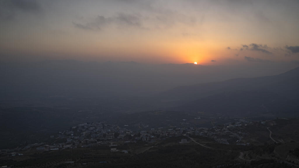 Le soleil se couche derrière les montagnes près des villes de Kiryat Shmona et Metula, situées près de la frontière avec le Liban, vu de Mas'ade, un village du plateau du Golan contrôlé par Israël, dimanche 23 juin 2024.