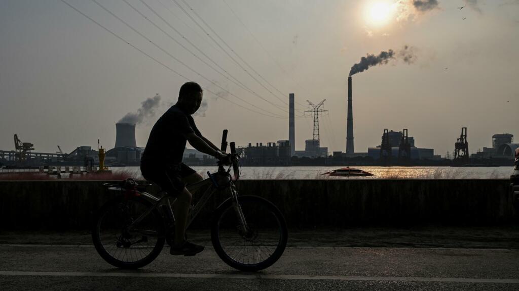 Homem passeia de bicicleta perto de usina a carvão em Shangai, na China (28/09/2021).