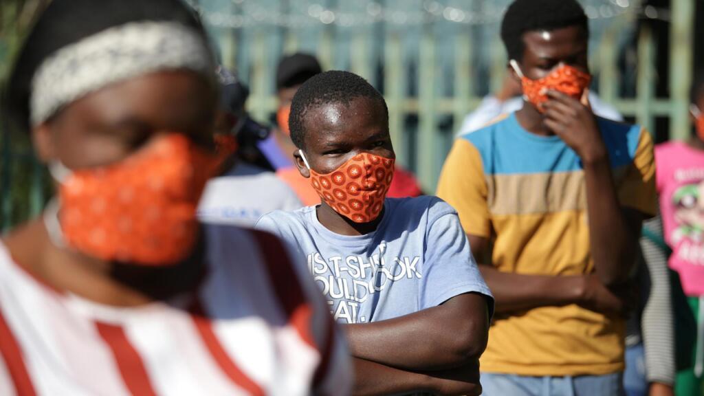 Des jeunes sud-africains portent des masques alors qu'ils attendent des colis de nourriture du capitaine de l'équipe nationale de rugby sud-africaine Siya Kolisi et des membres de la Fondation Nelson Mandela au nord de de Johannesburg, le 25 avril 2020.