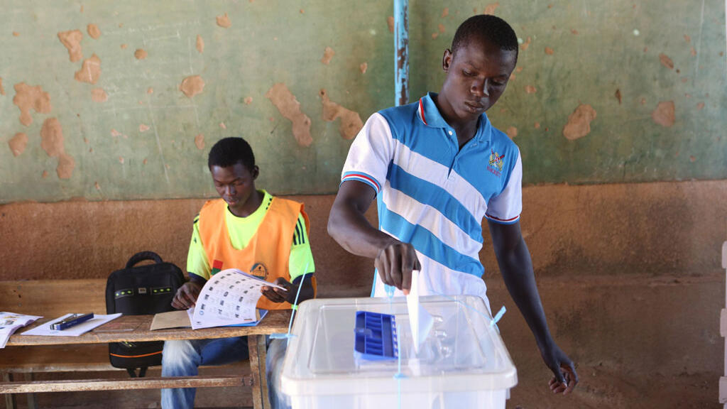 Un homme déposant son bulletin de vote dans l'urne au Burkina Faso.