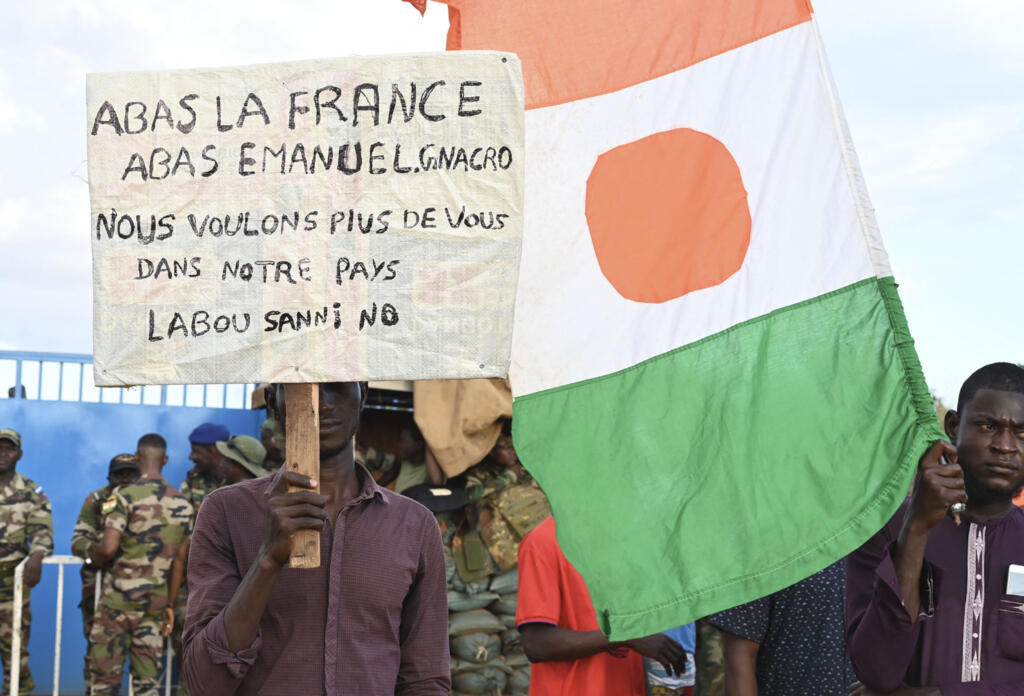 Um apoiador do Conselho Nacional de Salvaguarda da Pátria (CNSP) do Níger segura um cartaz contra Emanuem Macron, “não queremos mais você em nosso país", enquanto os manifestantes se reúnem ao lado da base aérea nigerina e francesa em Niamey, em 3 de setembro de 2023.