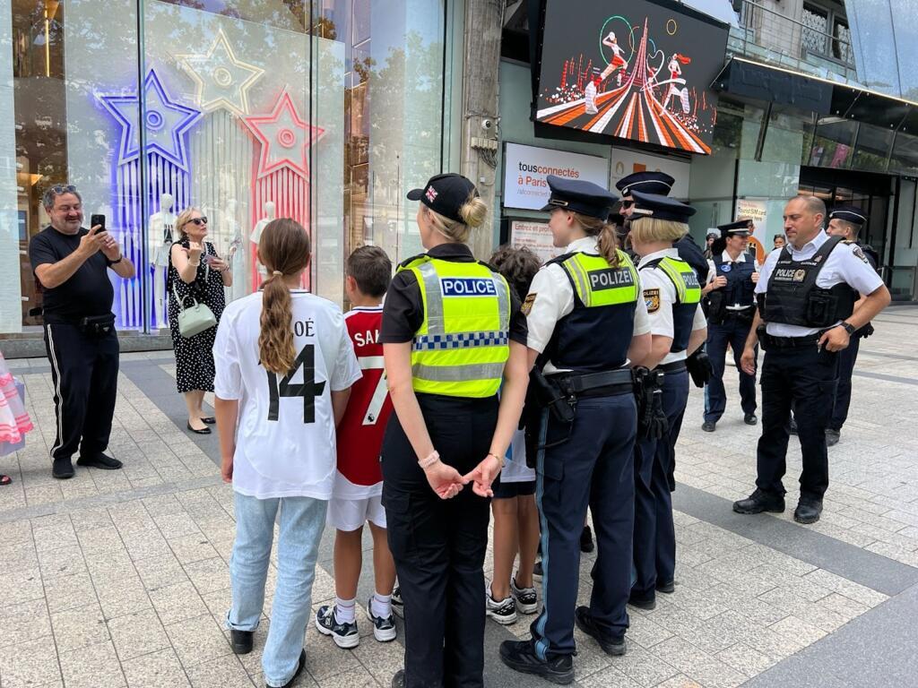 Les policiers étrangers enchaînent les photos avec les passants, Avenue des Champs Élysées, à Paris.
